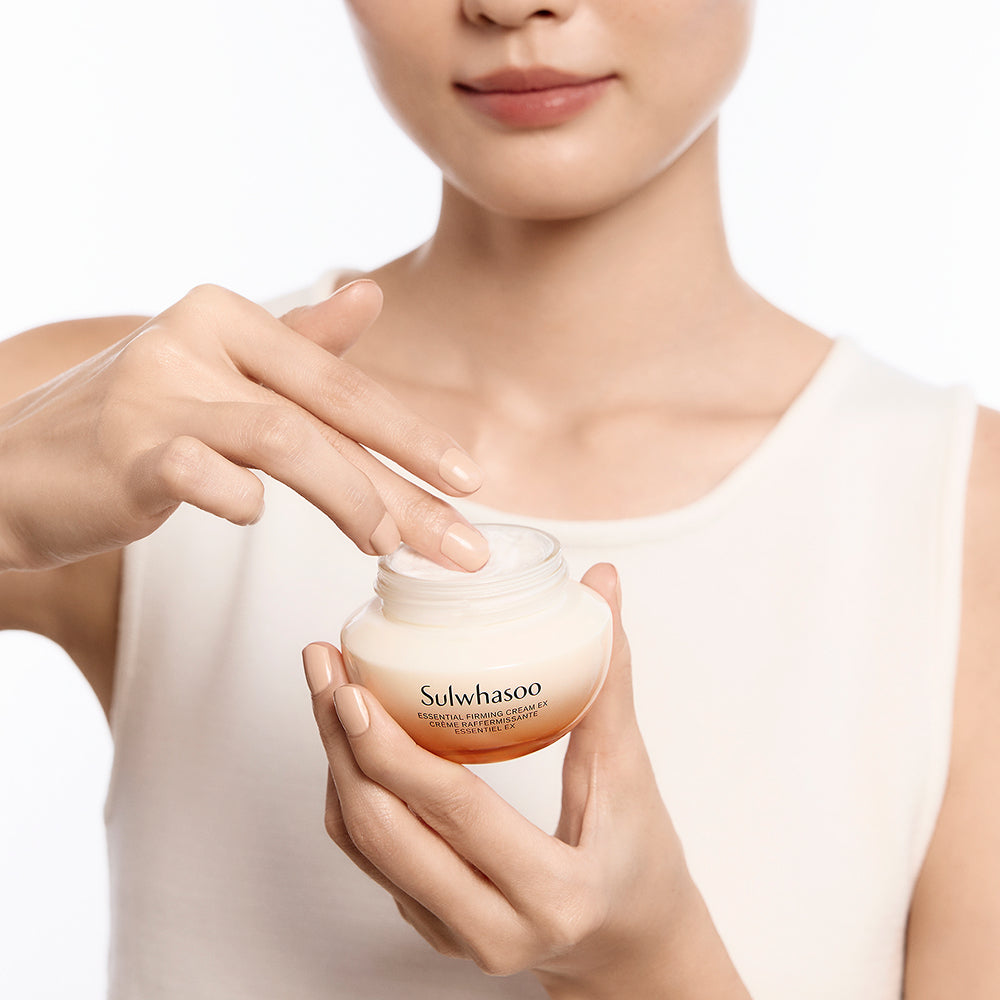 Décris l'image en français : SULWHASOO Essential Comfort Firming Cream 75ml, pot de crème visage SULWHASOO, mains appliquant sur peau