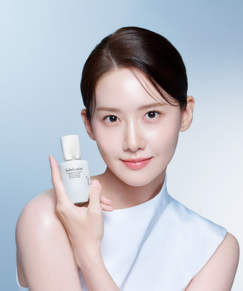 SULWHASOO Lumiwise Brightening Ampoule Serum 30ml par Sulwhasoo, flacon blanc tenu par une femme sur fond bleu.