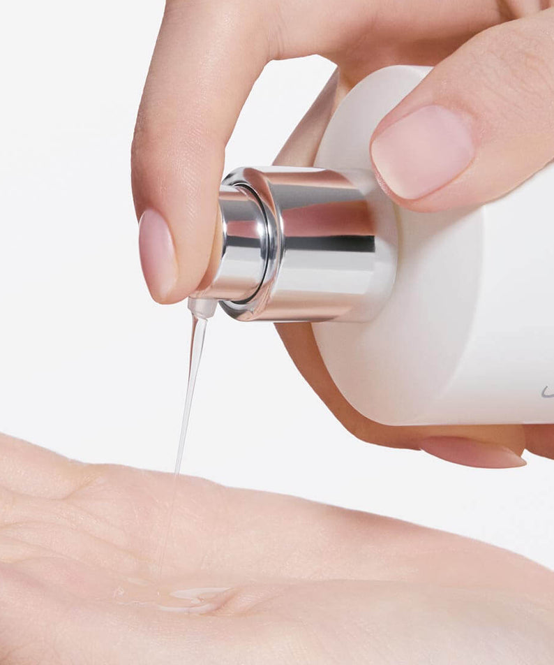 SULWHASOO Lumiwise Brightening Essence Water 150ml : application du sérum éclaircissant, flacon et mains, fond clair.