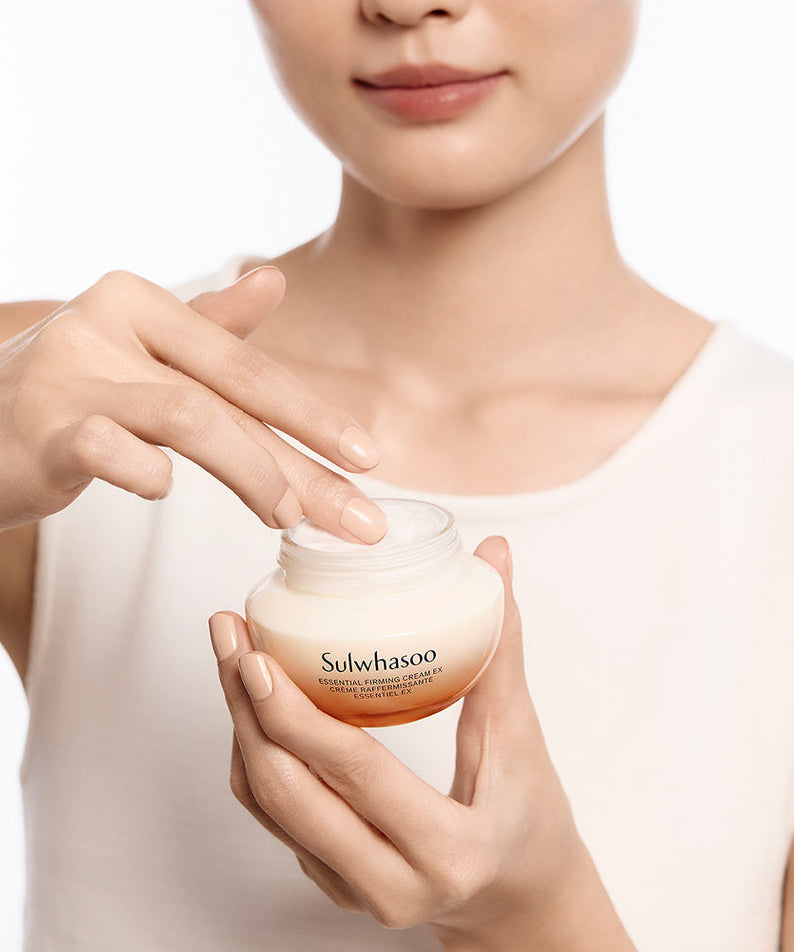 Femme appliquant la crème SULWHASOO Essential Comfort Firming Cream 75ml sur la peau, soin de beauté raffermissant.
