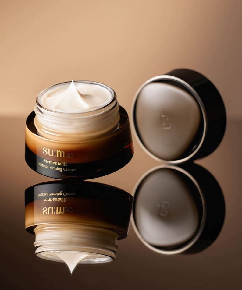 Crème raffermissante intense SU:M37 Fermentalift 50ml ouverte avec couvercle, sur fond marron élégant.