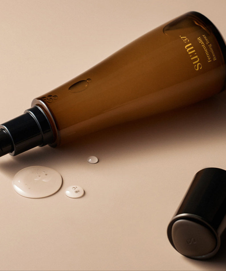SU:M37 Fermentalift boosting toner 150ml en bouteille translucide posée sur fond beige, formulé pour rehausser l'éclat de la peau.