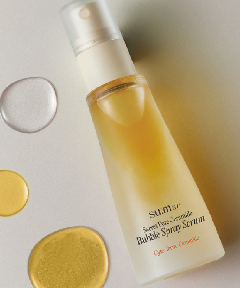Flacon du SU:M37 Secret Pore Ceramide Bubble Oil Essence Mist 60ml avec liquide doré et gouttes de sérum sur fond clair.