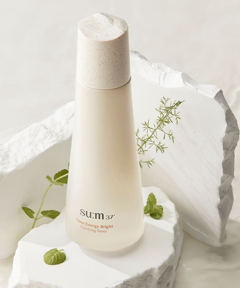 SU:M37 Time Energy Bright Clarifying Toner 170ml de la marque SU:M37, flacon sur pierre blanche avec feuilles et lumière.