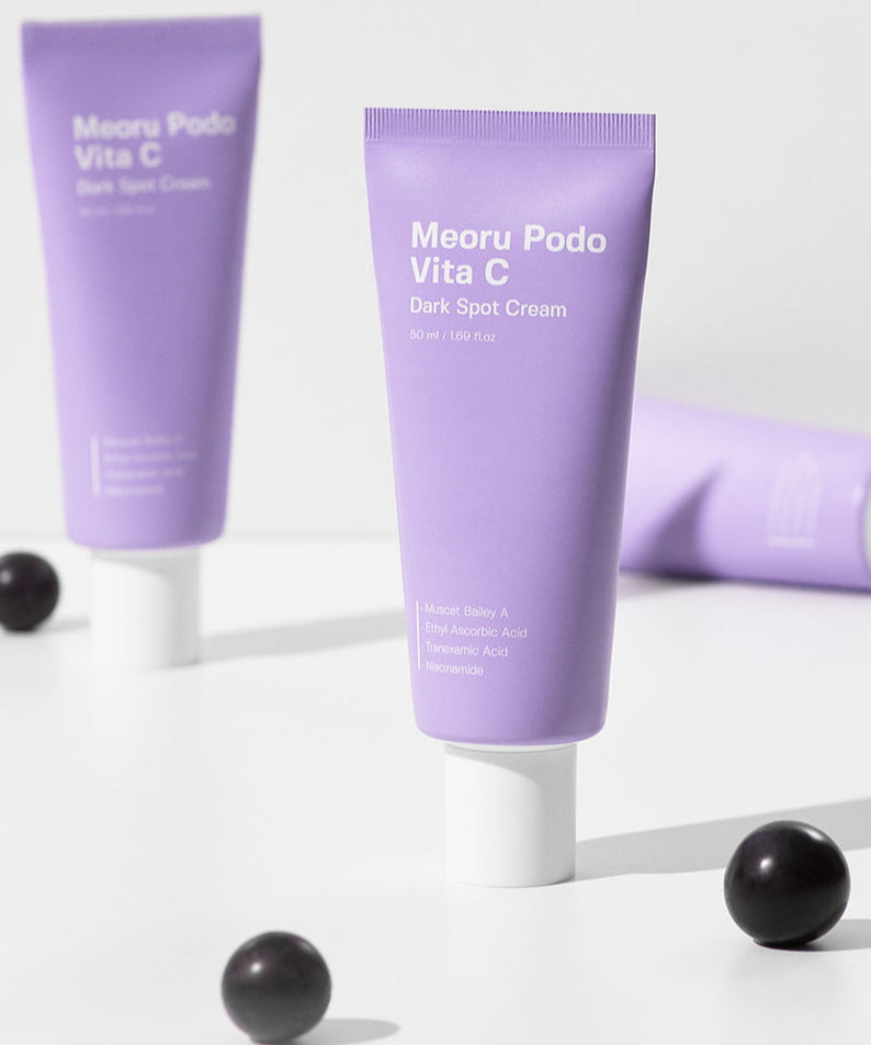 SUNGBOON EDITOR Meoru Podo Vita C Dark Spot Cream 50ml sur fond blanc, tubes violets et billes noires, contexte beauté.