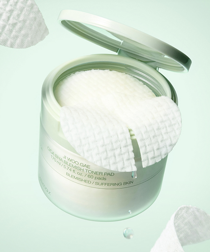 Pot de CELIMAX Ji Woo Gae Cica BHA Blemish Toner Pad 60 pads ouvert avec un tampon visible sur fond vert.