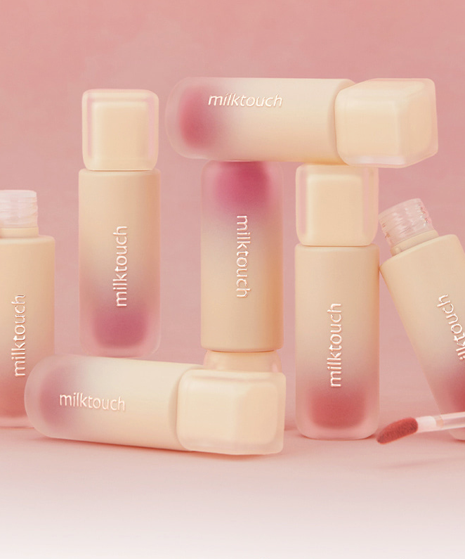 Flacons de MILK TOUCH Spread Fit Blur Tint avec applicateurs et teintes rose sur fond pastel.