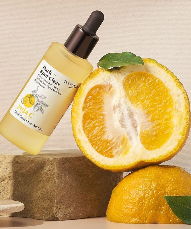 SKINFOOD Yuja C Dark Spot Clear Serum 50ml de Skinfood, flacon jaune sur agrumes, contexte visuel skincare