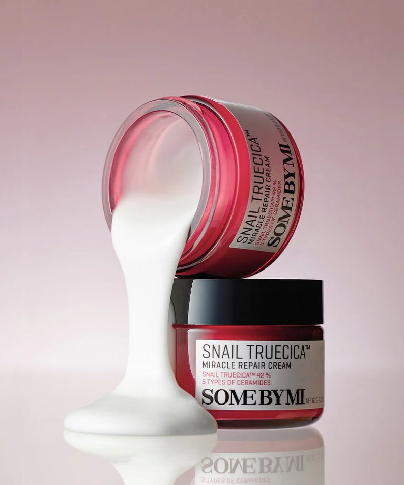 SOME BY MI Snail Truecica Miracle Repair Cream 60g, crème SOME BY MI sur fond rose, pot ouvert avec texture blanche.