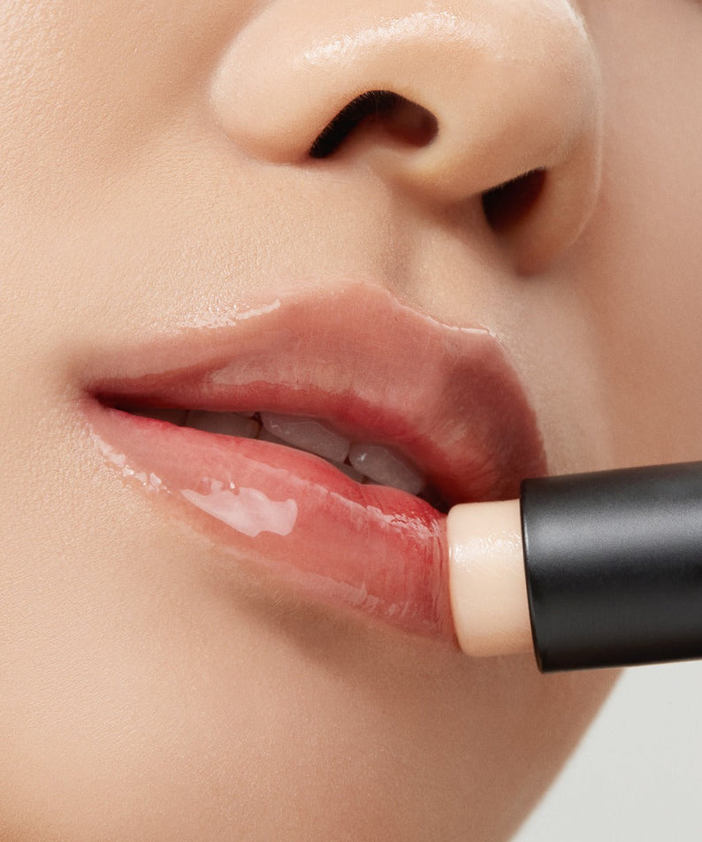 Application de TALITHA KOUM Lipcure Balmtik sur les lèvres, mettant en valeur la texture hydratante et brillante du baume à lèvres.