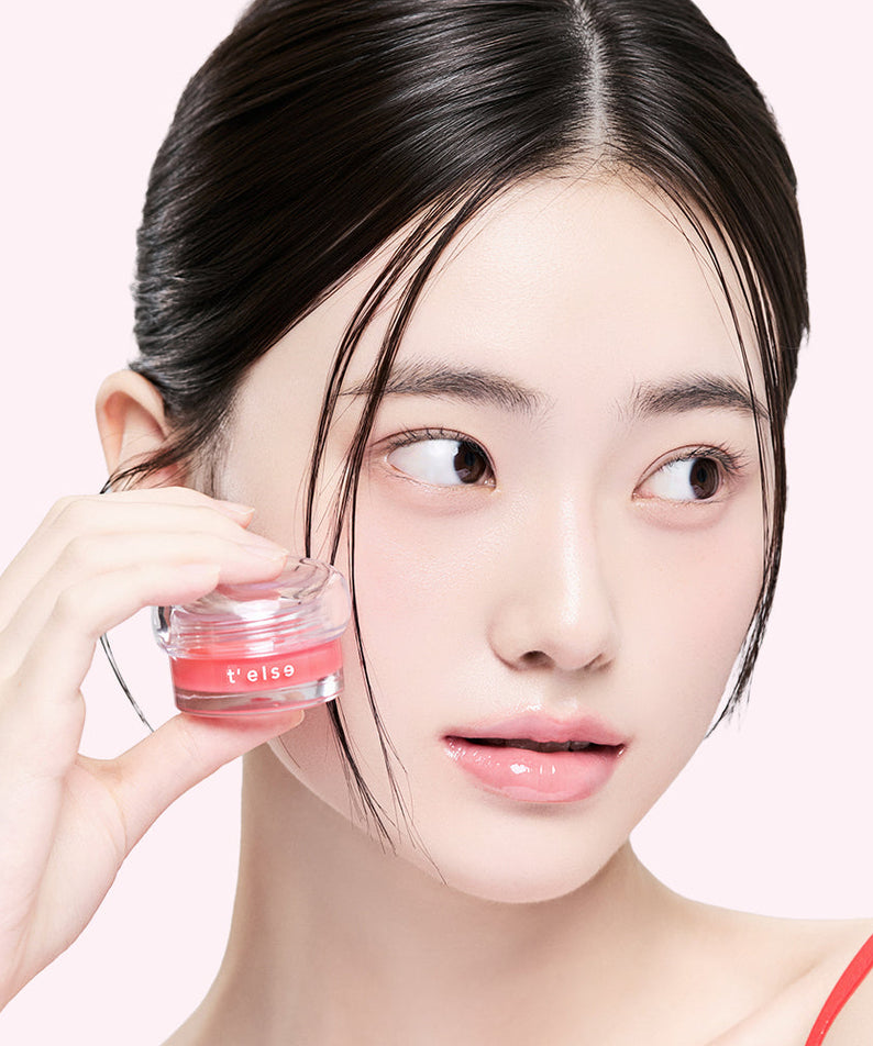 Décris l’image en français : T'ELSE Plumping Glow Jelly Pot 9g, marque T'ELSE, pot cosmétique tenu par une femme sur fond clair.