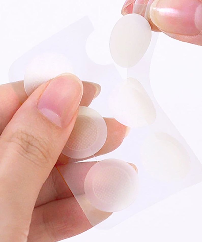 THE SAEM Golden Berry C Dark Spot Patch : mains appliquant des patchs sur la peau, photo produit marque THE SAEM.