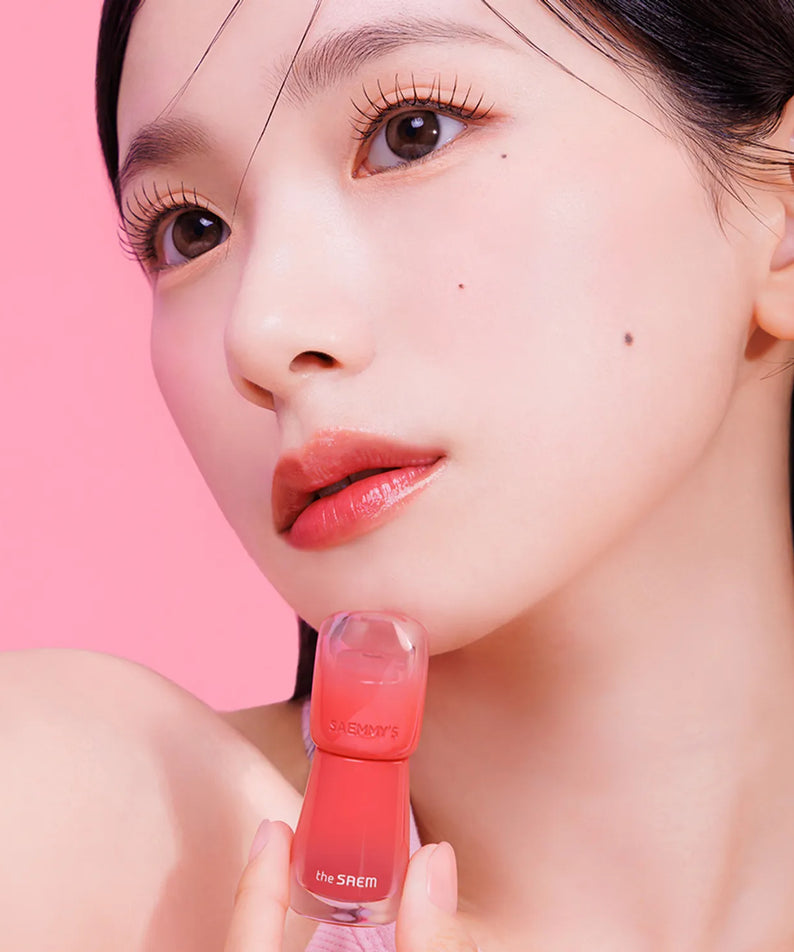 THE SAEM Saemmy's Aid Shot Tint, produit de la marque, maquillage lèvres sur fond rose, gros plan visage