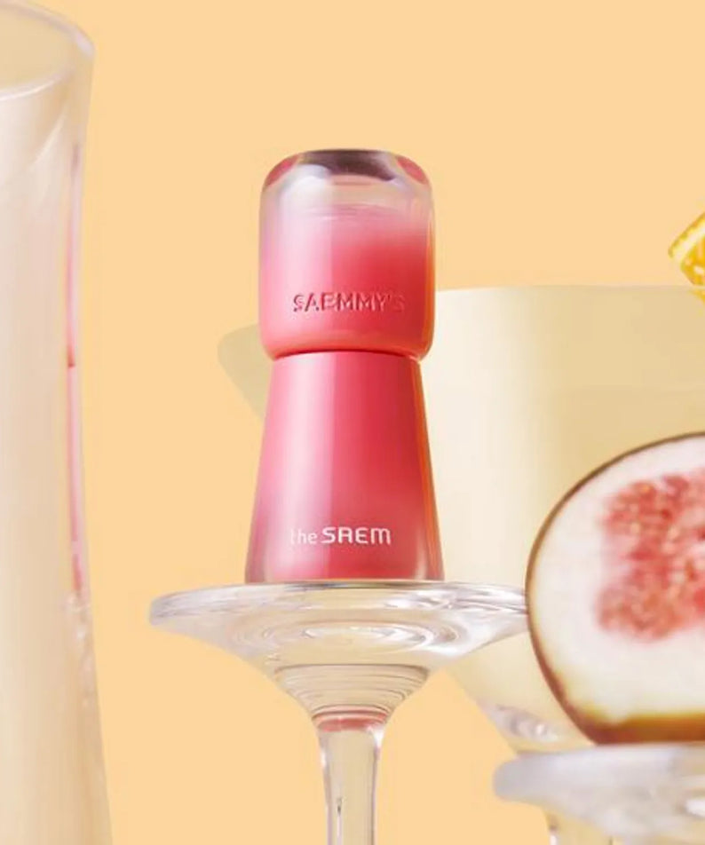 THE SAEM Saemmy's Aid Shot Tint de la marque The Saem, flacon rose en studio avec agrumes sur fond beige
