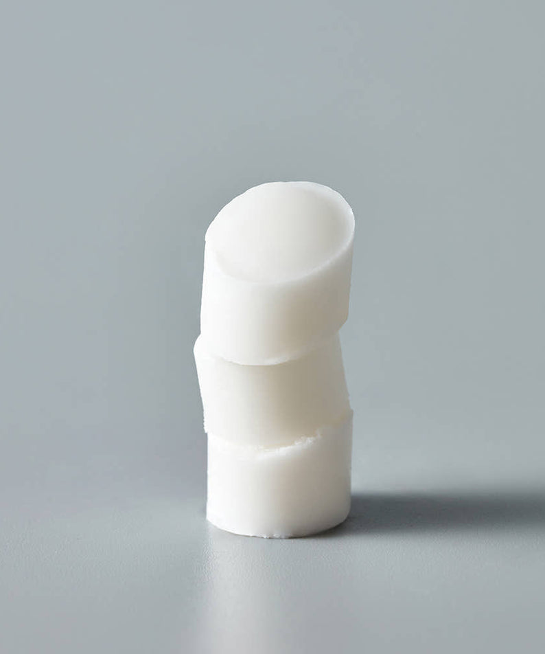 Décris l'image en français: THE SAEM Soft Blurring Primer Lip Balm de la marque THE SAEM, bâton de baume blanc sur fond gris.