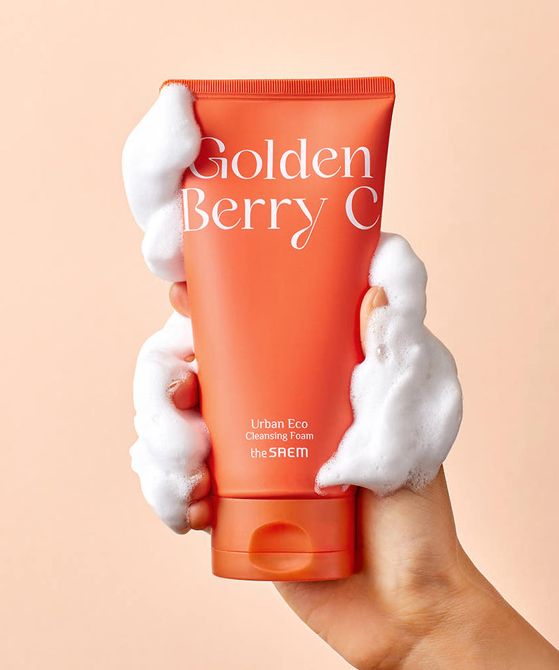 THE SAEM Urban Eco Golden Berry C Cleansing Foam 150ml de la marque, tube orange tenu avec mousse sur fond pastel.