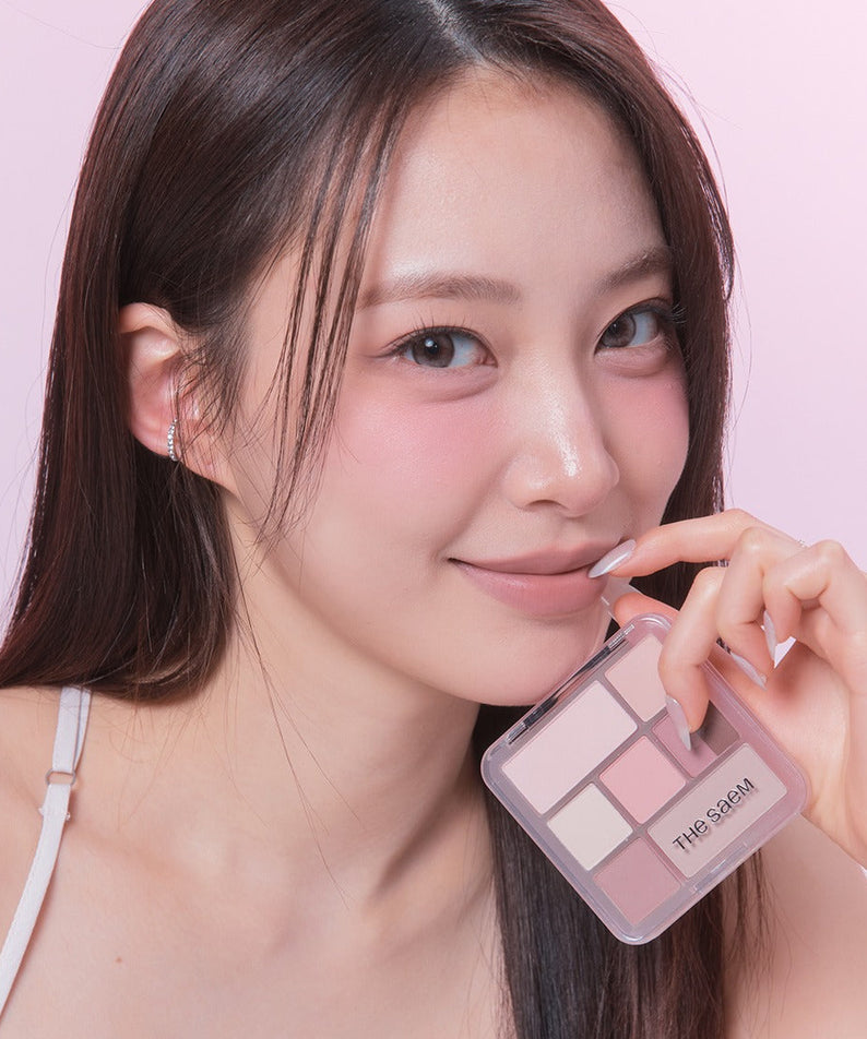 Portrait maquillage avec THE SEAM Shadow Box Palette, marque THE SEAM, palette ombres dans un décor rose pastel.