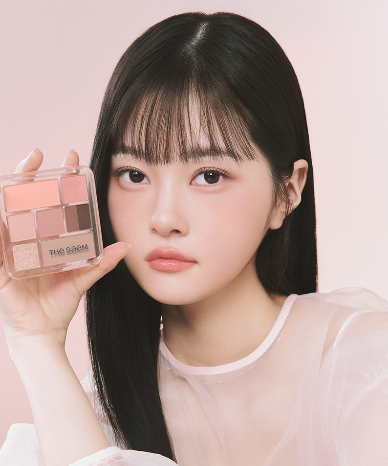 THE SEAM Shadow Box Palette, maquillage dans un décor rose; une femme présente la palette de la marque THE SEAM.