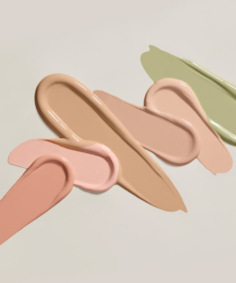 Différentes teintes de THE SAEM Cover Perfection Pen Concealer étalées artistiquement sur une surface.