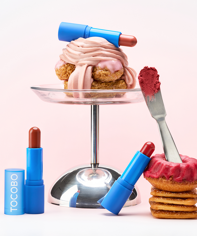 TOCOBO Powder Cream Lip Balm, tube bleu et crème sur dessert rose sur fond clair, style beauté pâtisserie