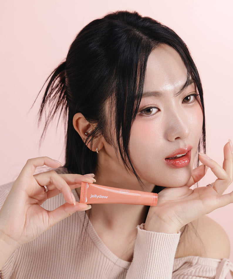 TONE FIT SUN Jelly Dew Glossy Balm 10g, baume brillant en tube; femme en studio sur fond rose, marque TONE FIT.