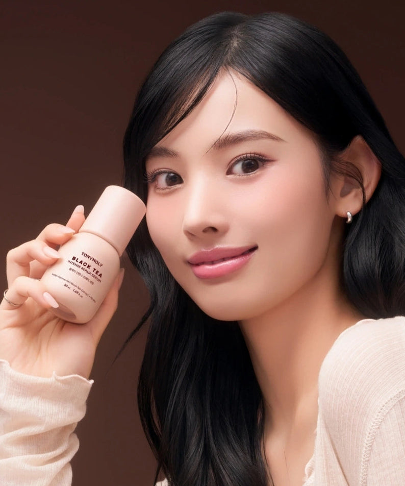 TONY MOLY Black Tea Intense Repair Serum 50ml, présenté sur fond brun, femme tenant le flacon, marque TONY MOLY