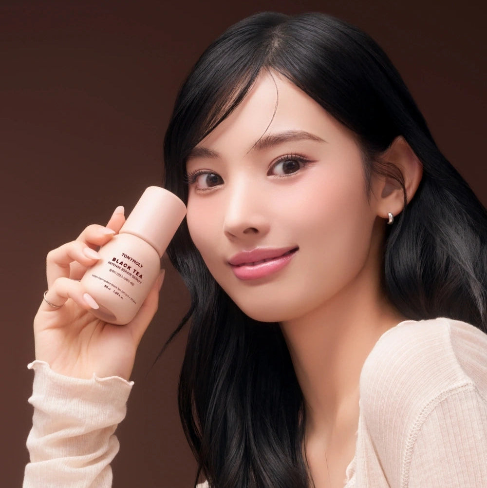 TONY MOLY Black Tea Intense Repair Serum 50ml, présenté sur fond brun, femme tenant le flacon, marque TONY MOLY