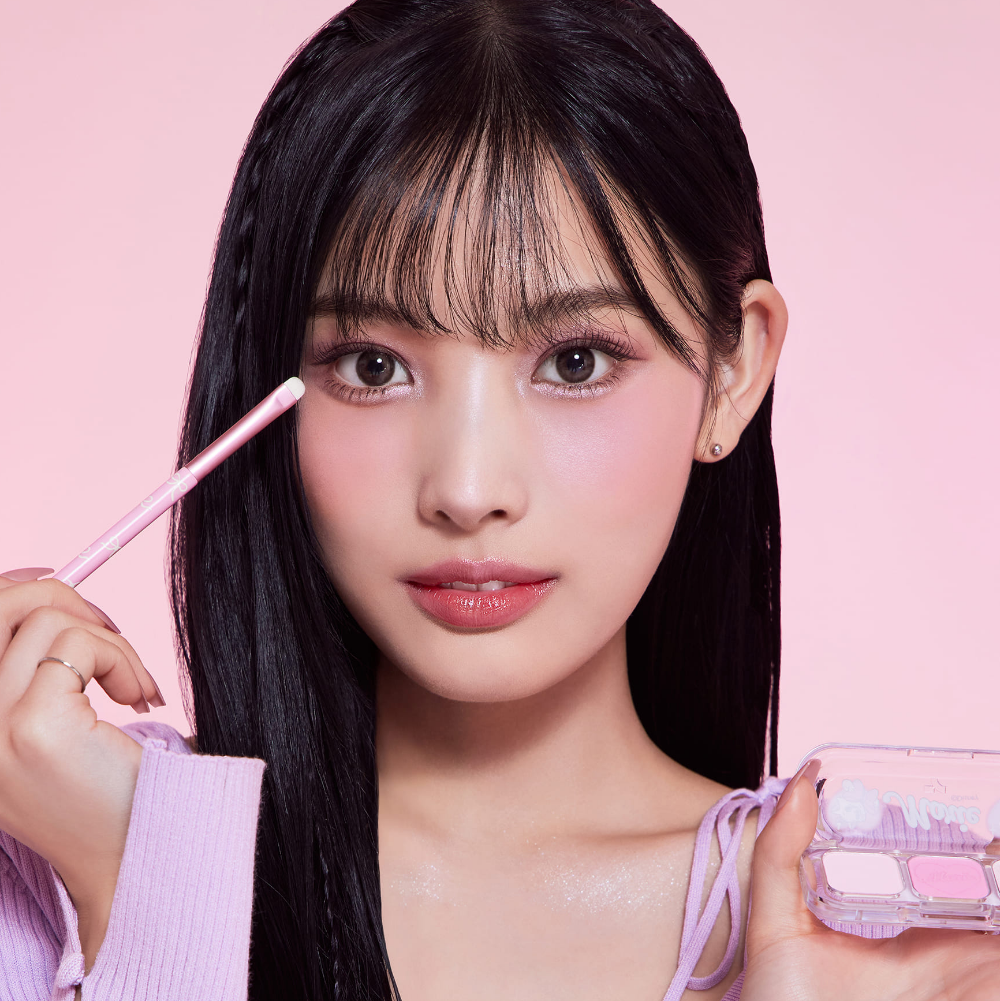 Décris l'image en français : TONY MOLY Eyetone Eyeshadow Palette, maquillage yeux sur fond rose avec la marque.