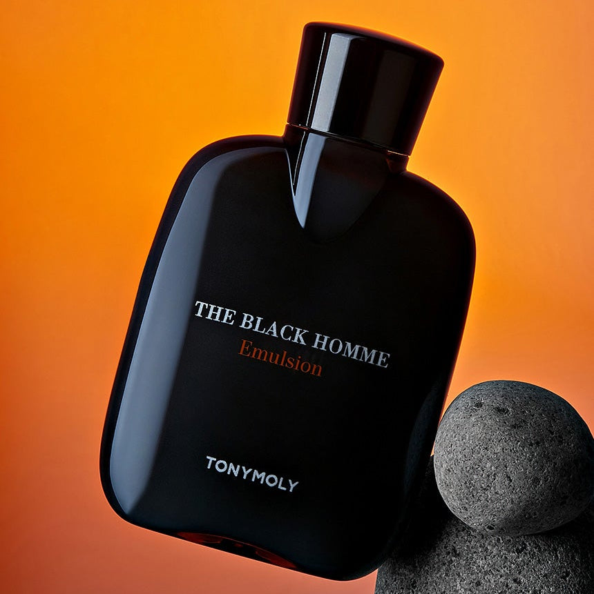 TONYMOLY The Black Homme Emulsion 160ml, flacon noir sur fond orange, avec pierre grise pour contexte visuel.