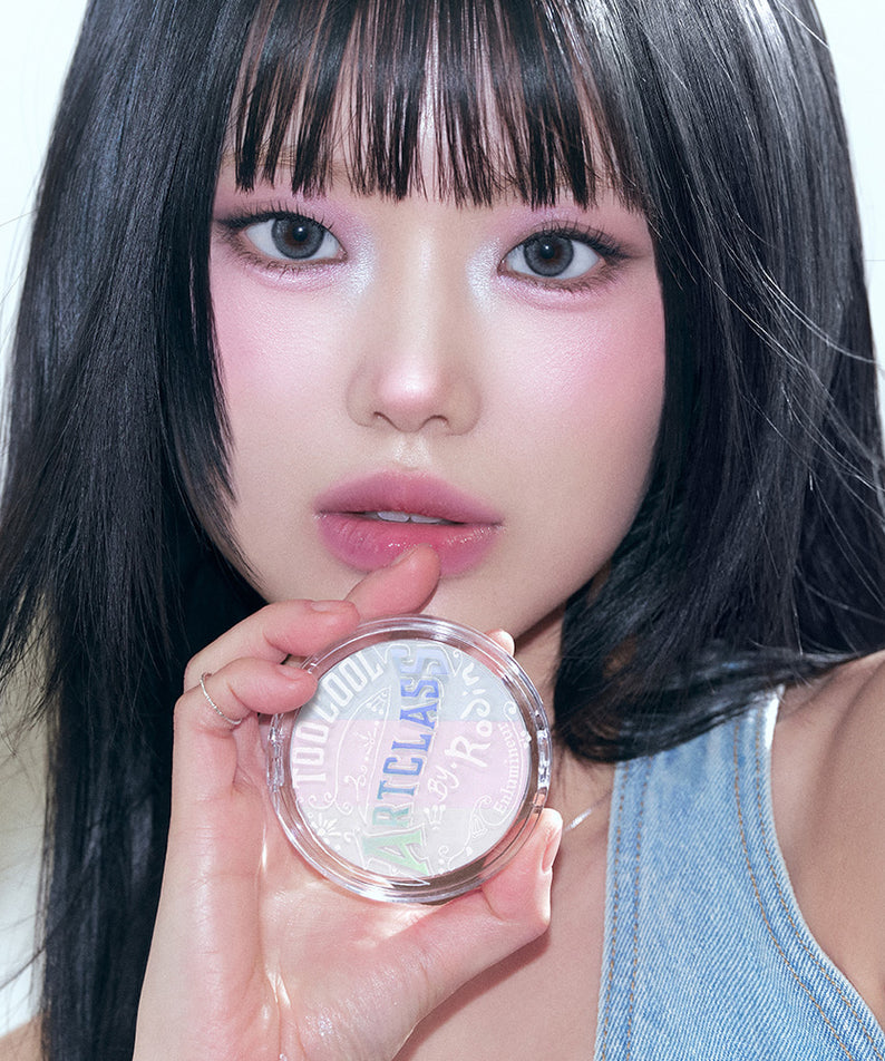 Femme tenant le TOO COOL FOR SCHOOL Art Class By Rodin Highlighter, maquillage lumineux sur le visage. Produit beauté haut de gamme.