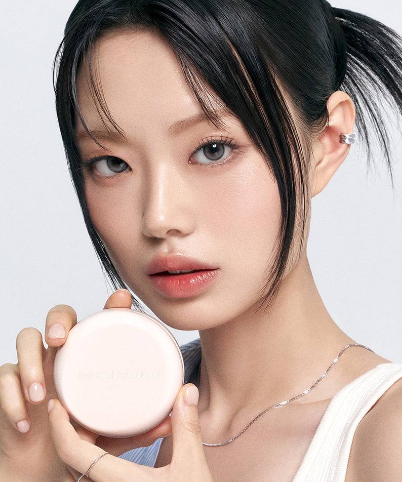 Femme tenant un TOO COOL FOR SCHOOL Fixing Dew Cushion [Main Product + Refill], maquillage effet lumineux.