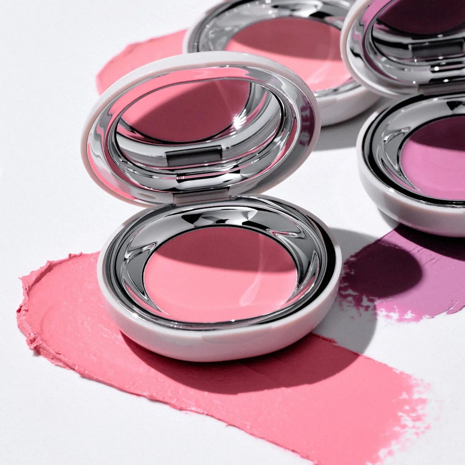 TOOQ Satin Peach Blossom : maquillage rose avec boîtiers métalliques, reflets et éclaboussures sur fond clair.