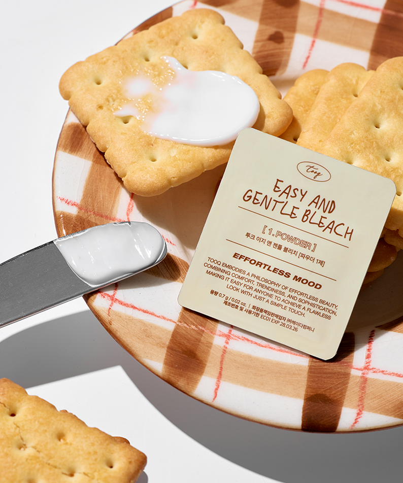 TOOQ Easy And Gentle Bleach sur une planche avec des biscuits, illustrant un modèle doux et efficace pour des résultats éclatants.