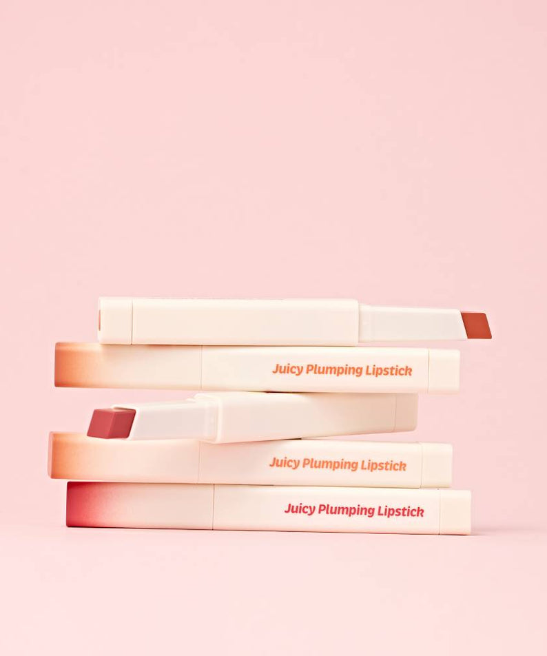 TOUCH IN SOL Vegan Again Juicy Plumping Lipstick empilés sur fond rose, ajoutant une touche élégante et sophistiquée à votre look.