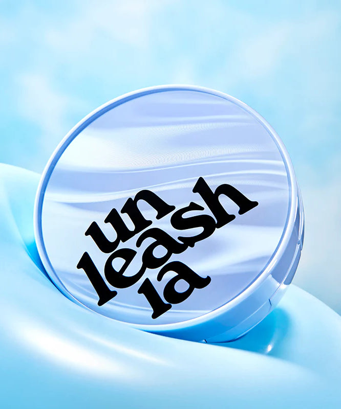 UNLEASHIA Babe Skin Baby Blue Cushion avec ciel bleu en arrière-plan. Emballage élégant montrant le logo unique d'UNLEASHIA, prêt à séduire.