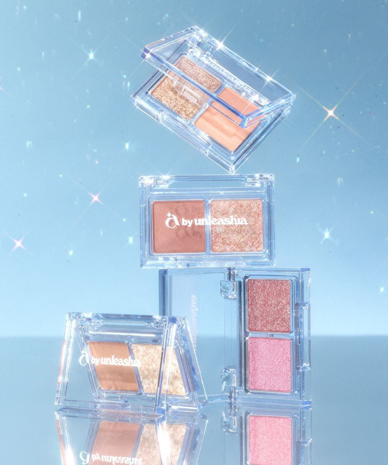 UNLEASHIA Cotton Candy Face Palette de la marque UNLEASHIA, maquillage en palette transparente sur fond bleu scintillant.
