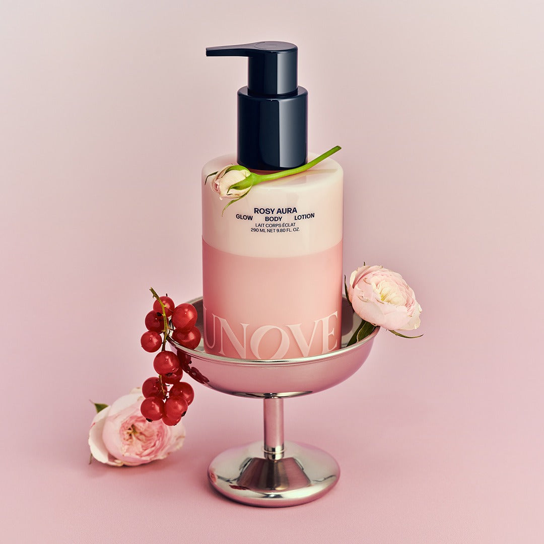 UNOVE Anove Glow Body Lotion 290ml, flacon-pompe sur support rose, décor fleurs et fruits, style cosmétique.