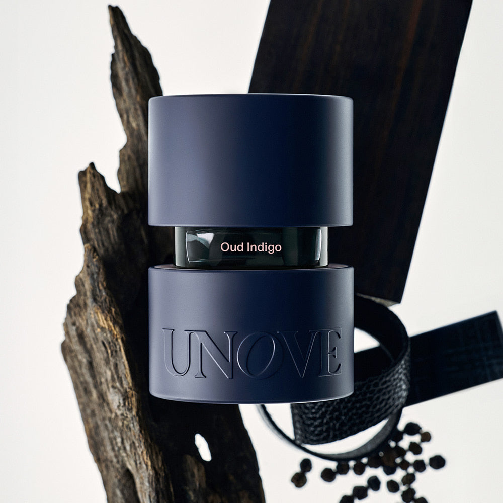 UNOVE Eau De Parfume de la marque UNOVE, flacon bleu sur étagère, contexte luxe avec décor noir et perles.