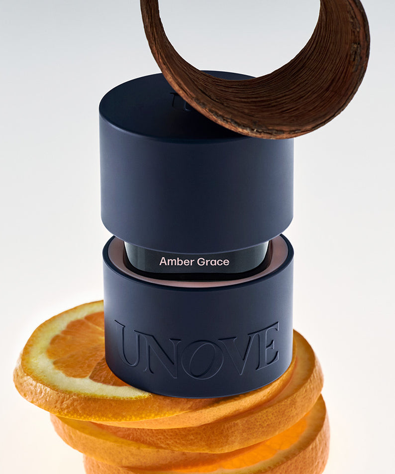 UNOVE Eau De Parfume de la marque UNOVE, flacon bleu sur fond blanc, entouré d’agrumes et de ruban bois.