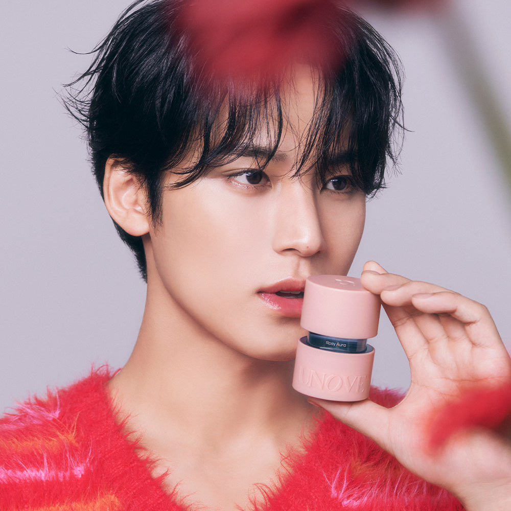 UNOVE Eau De Parfume de la marque UNOVE, flacon rose tenu près du visage d’un homme aux cheveux bruns, fond clair.