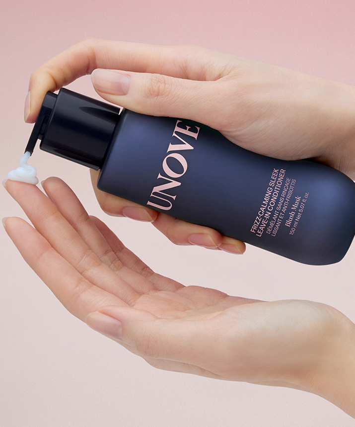 UNOVE Frizz Calming Sleek Leave-In Conditioner 150ml en main, produit UNOVE sur fond rose pastel, texture crème
