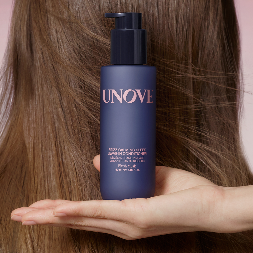 UNOVE Frizz Calming Sleek Leave-In Conditioner 150ml de la marque UNOVE, flacon bleu sur fond cheveux, mains tenant le produit