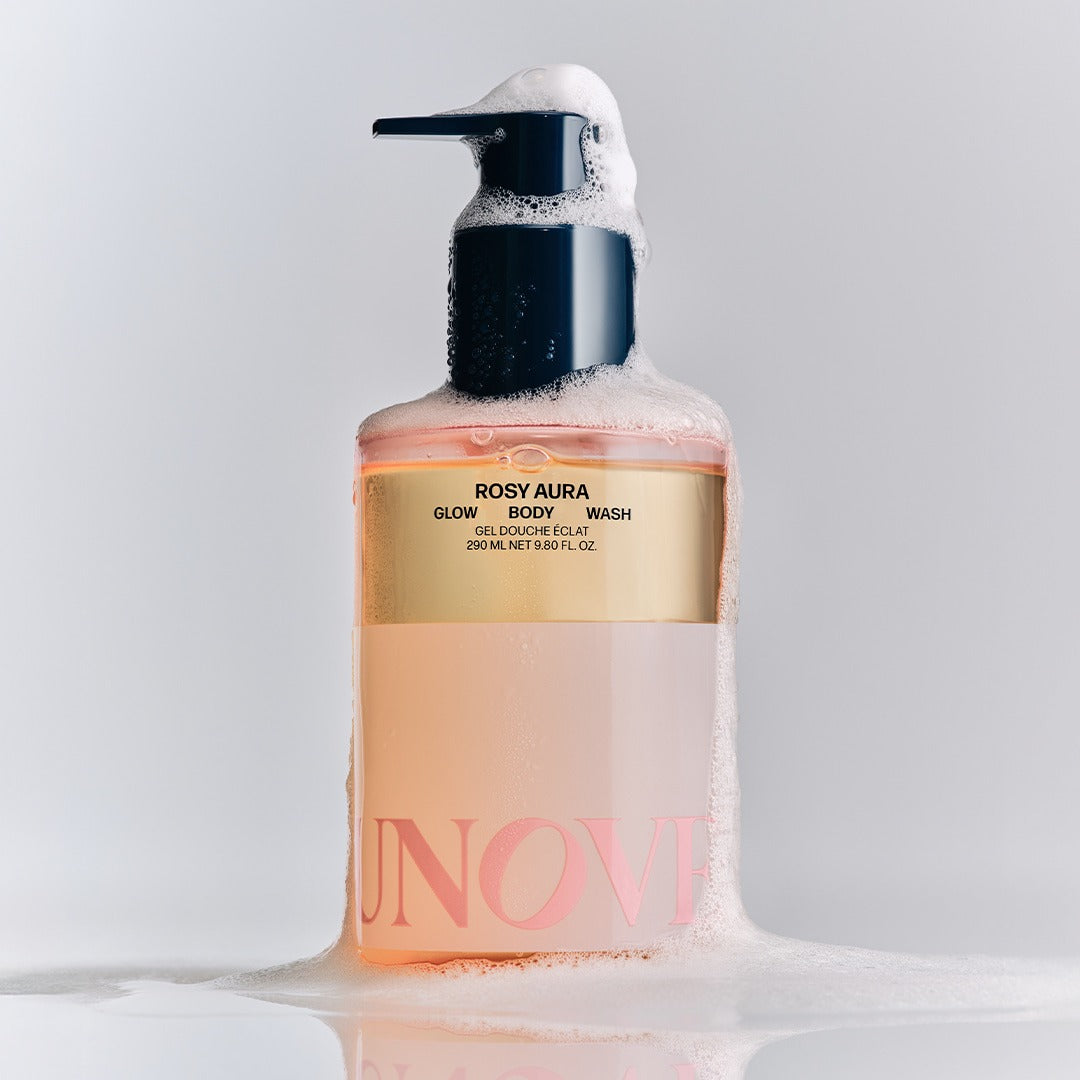 UNOVE Glow Body Wash 290ml, bouteille UNOVE sur fond blanc avec mousse et éclaboussures, contexte douche