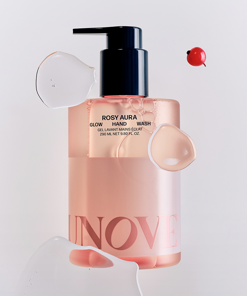 UNOVE Glow Hand Wash 290ml de la marque UNOVE, flacon pompe sur fond clair, mains et éclaboussures de savon.