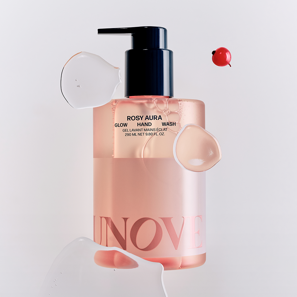 UNOVE Glow Hand Wash 290ml de la marque UNOVE, flacon pompe sur fond clair, mains et éclaboussures de savon.