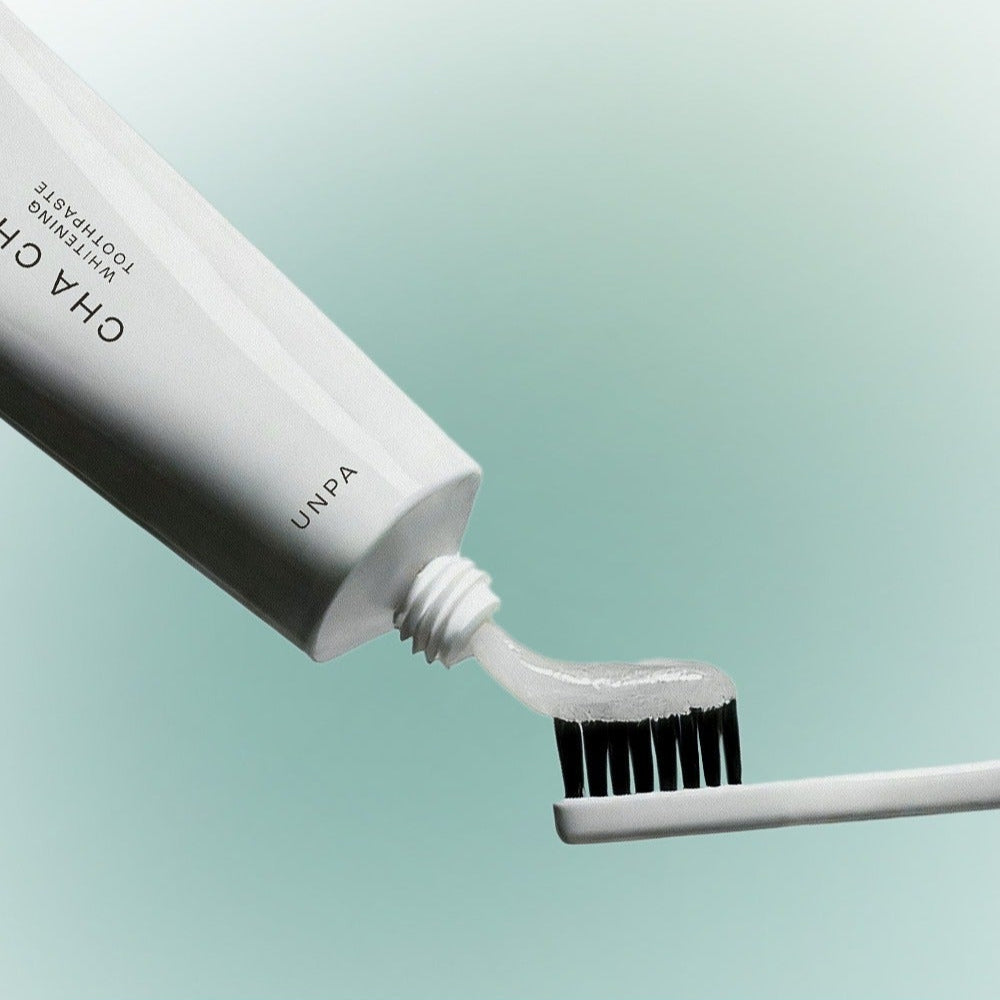 UNPA Chacha French Chamomile Vegan Whitening Toothpaste 90g, UNPA, tube et brosse sur fond bleu clair, style produit.