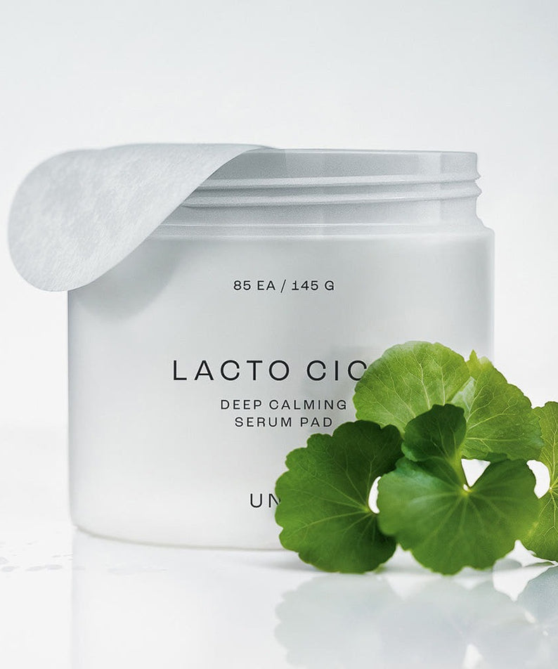 Décris l'image en français : UNPA Lacto Cica Deep Calming Serum Pad 85 Sheets, sérum pads UNPA sur fond blanc avec feuilles de cica.