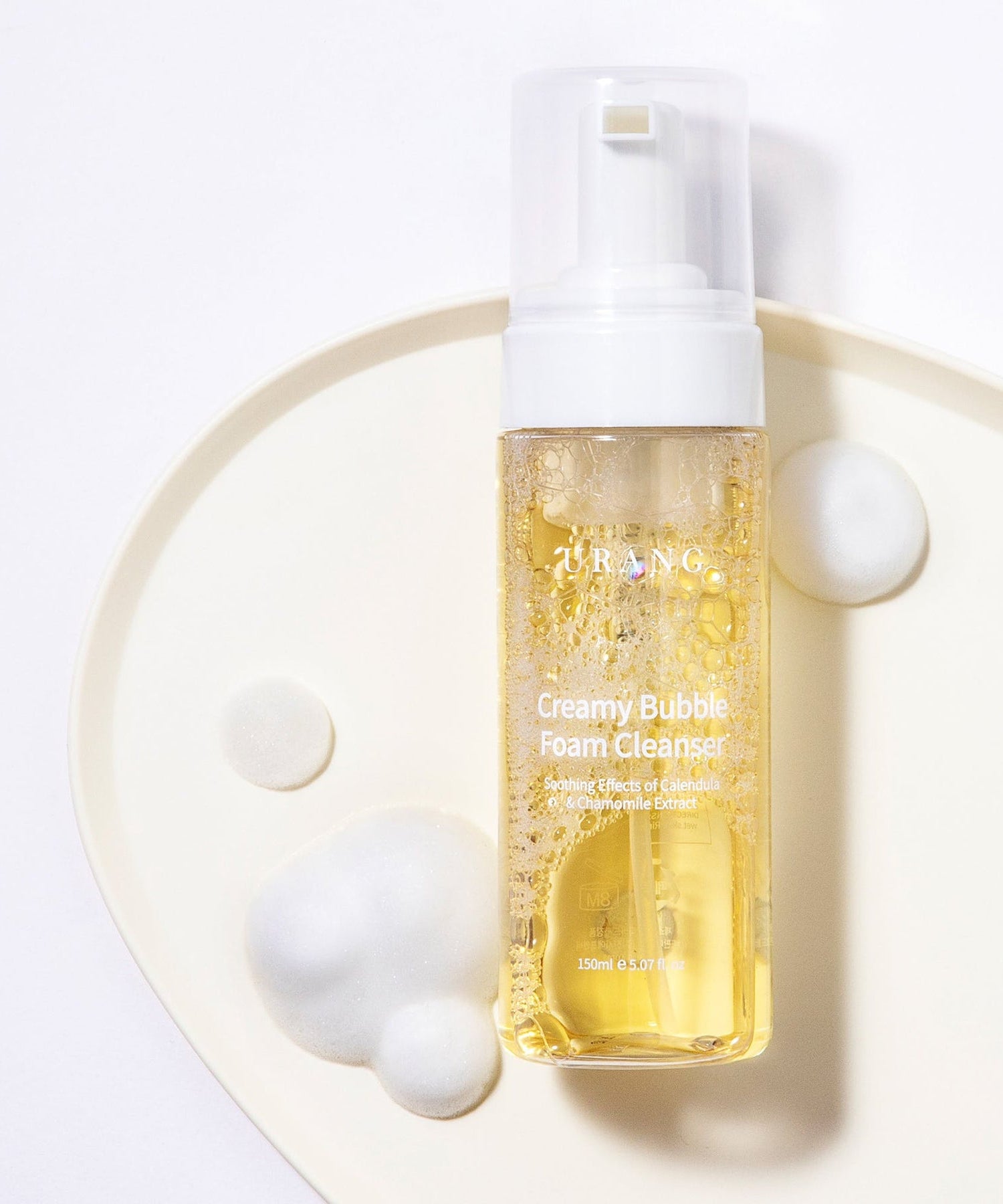 Flacon de 150ml de URANG Creamy Bubble Foam Cleanser avec mousse blanche autour, nettoyant visage moussant doux et hydratant.