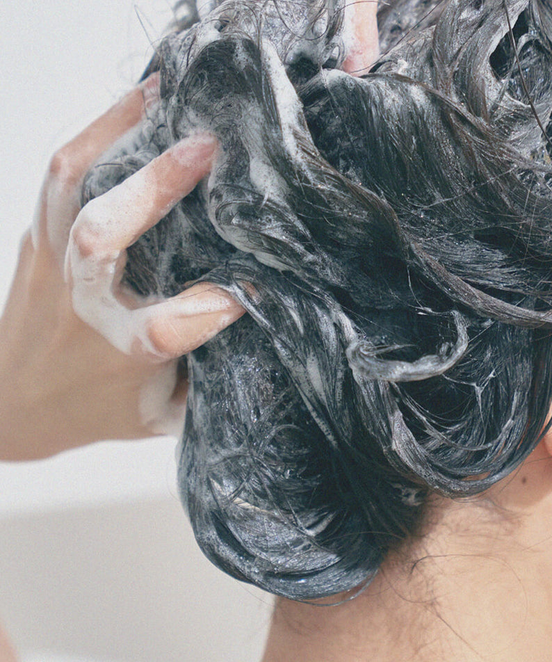 Application du shampooing URANG Moringa Scalp Strengthening Shampoo Bar sur cheveux mouillés, mousse nourrissante.