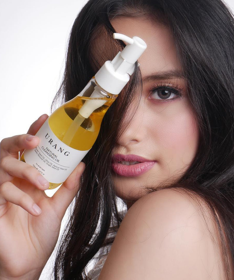 Femme tenant le URANG Natural Cleansing Oil 150ml devant son visage, produit de soin naturel pour nettoyage visage.
